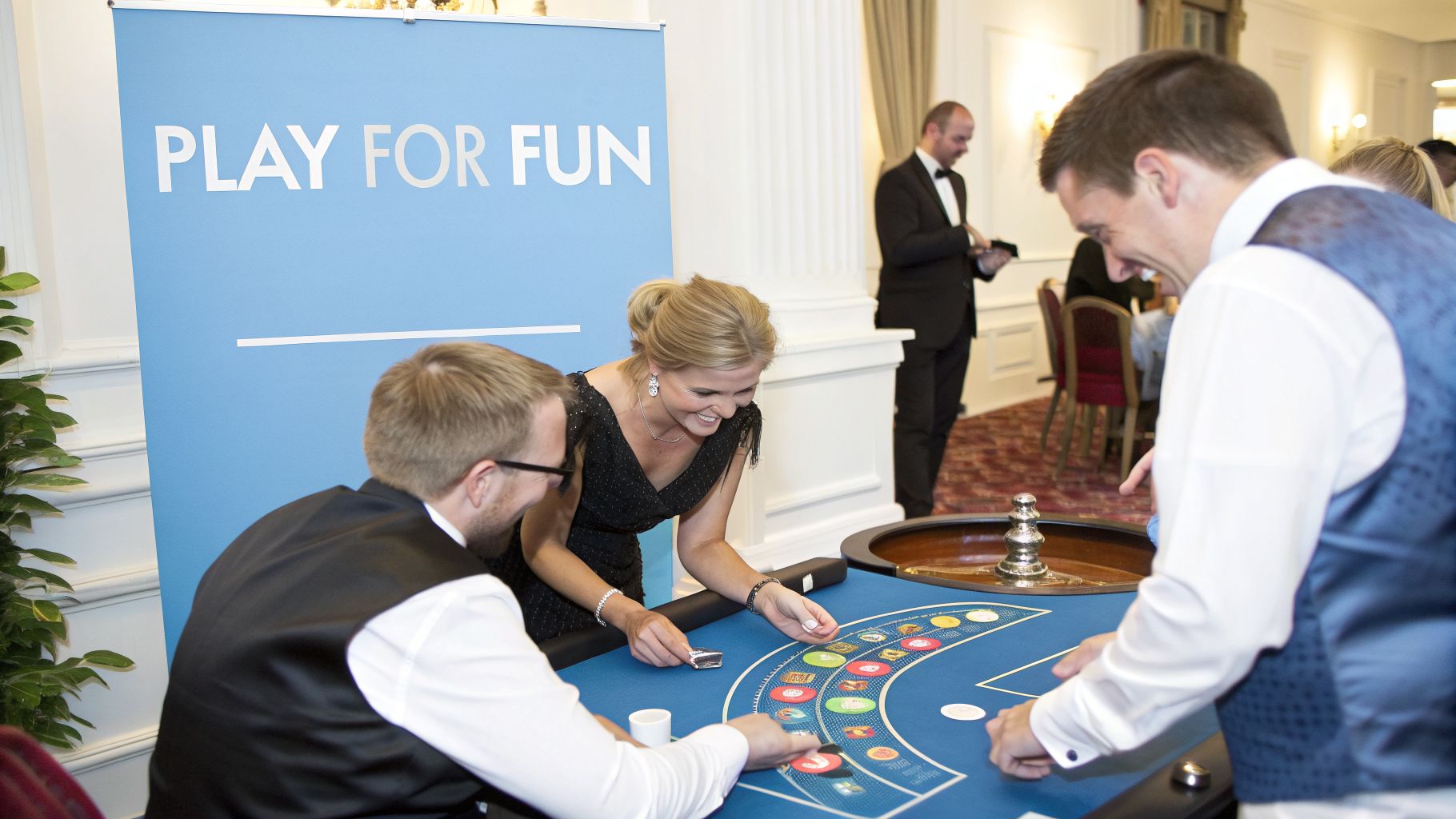 Guests smiling and engaging in a casino table game with chips at a wedding reception.