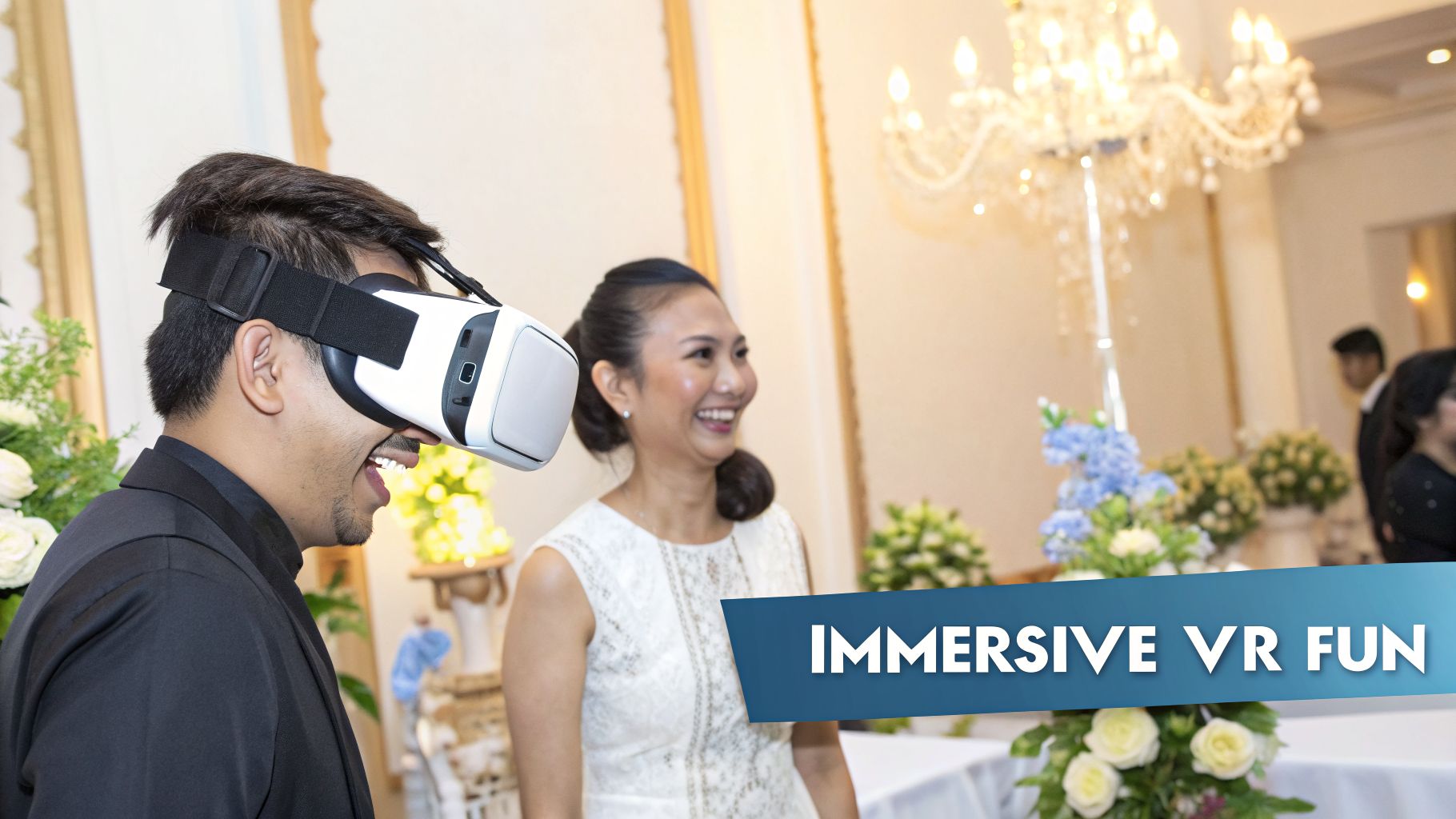 A man in a black suit laughs while wearing a VR headset at a lively event, with a smiling woman beside him.