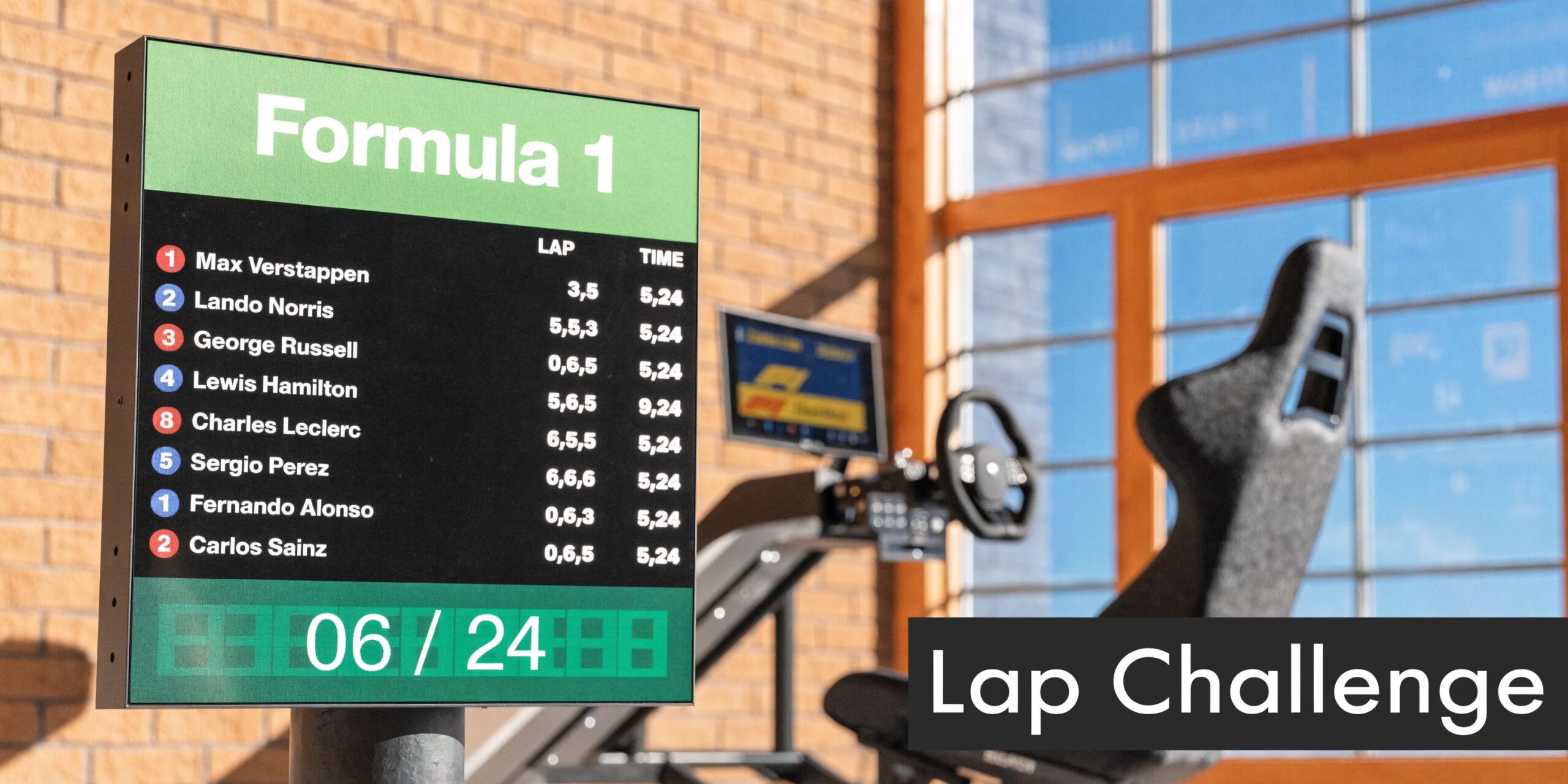 A Formula 1 scoreboard and racing simulator setup in a room with brick walls and large windows.
