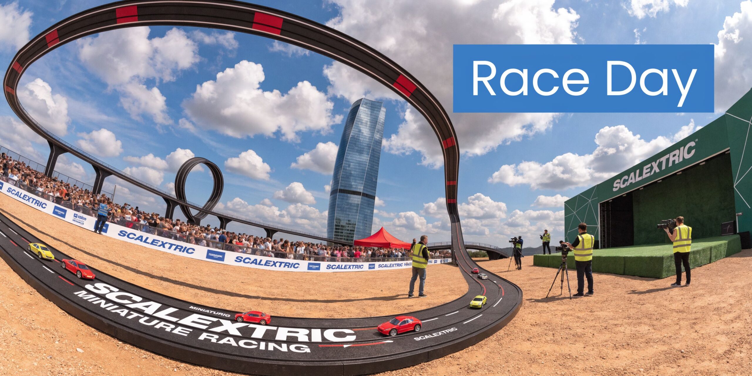 A giant outdoor Scalextric track with toy cars racing in front of a crowd and building.