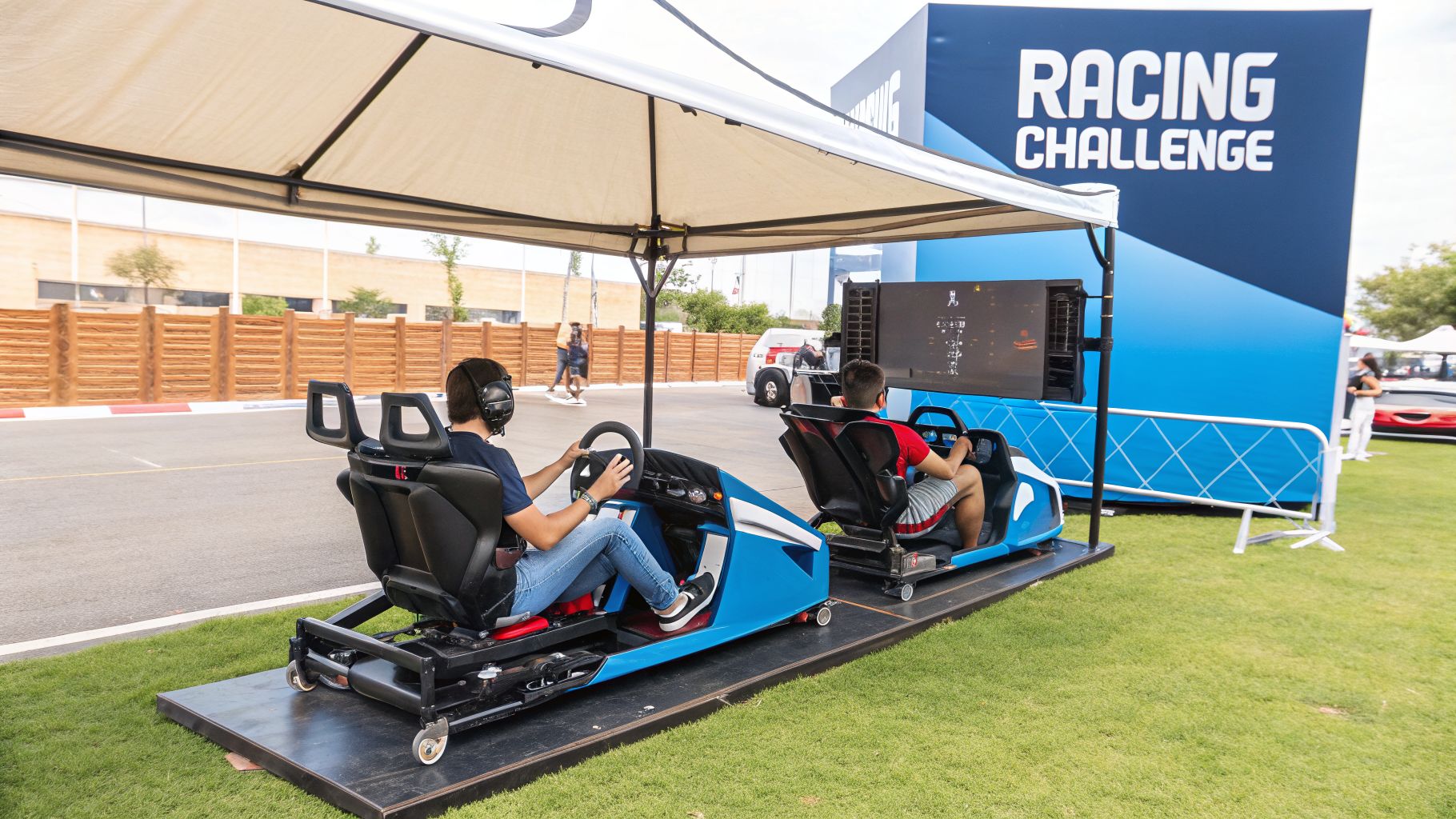 Two individuals enjoy racing simulators at an outdoor 'Racing Challenge' event.