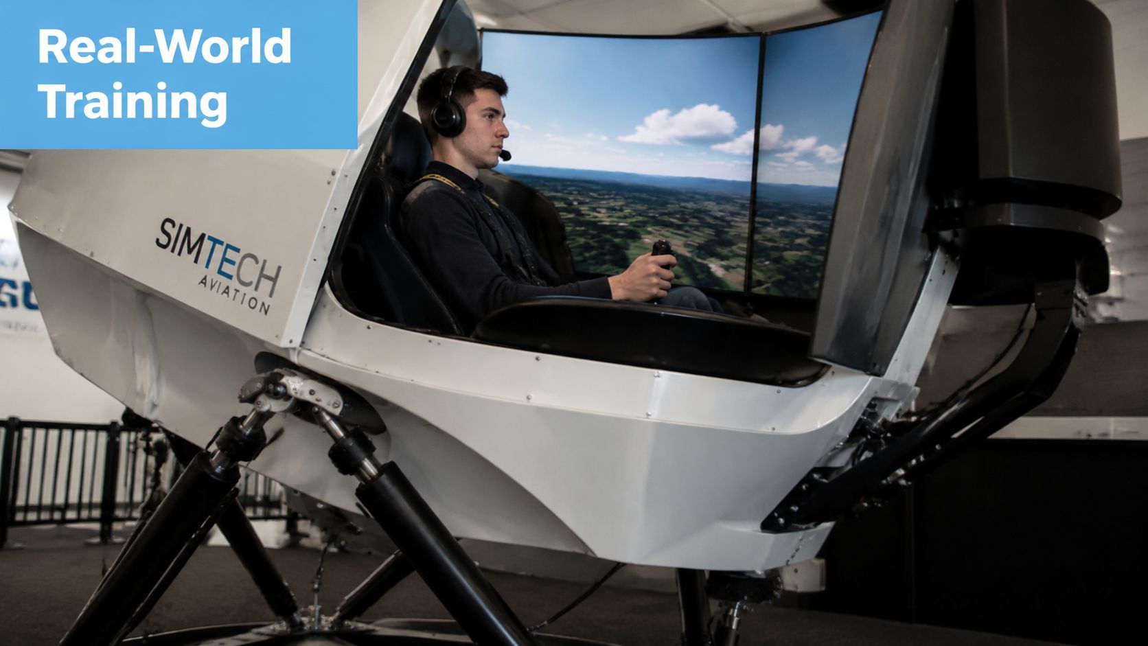 A student pilot training in a white full motion flight simulator system at SIMTECH Aviation facility.